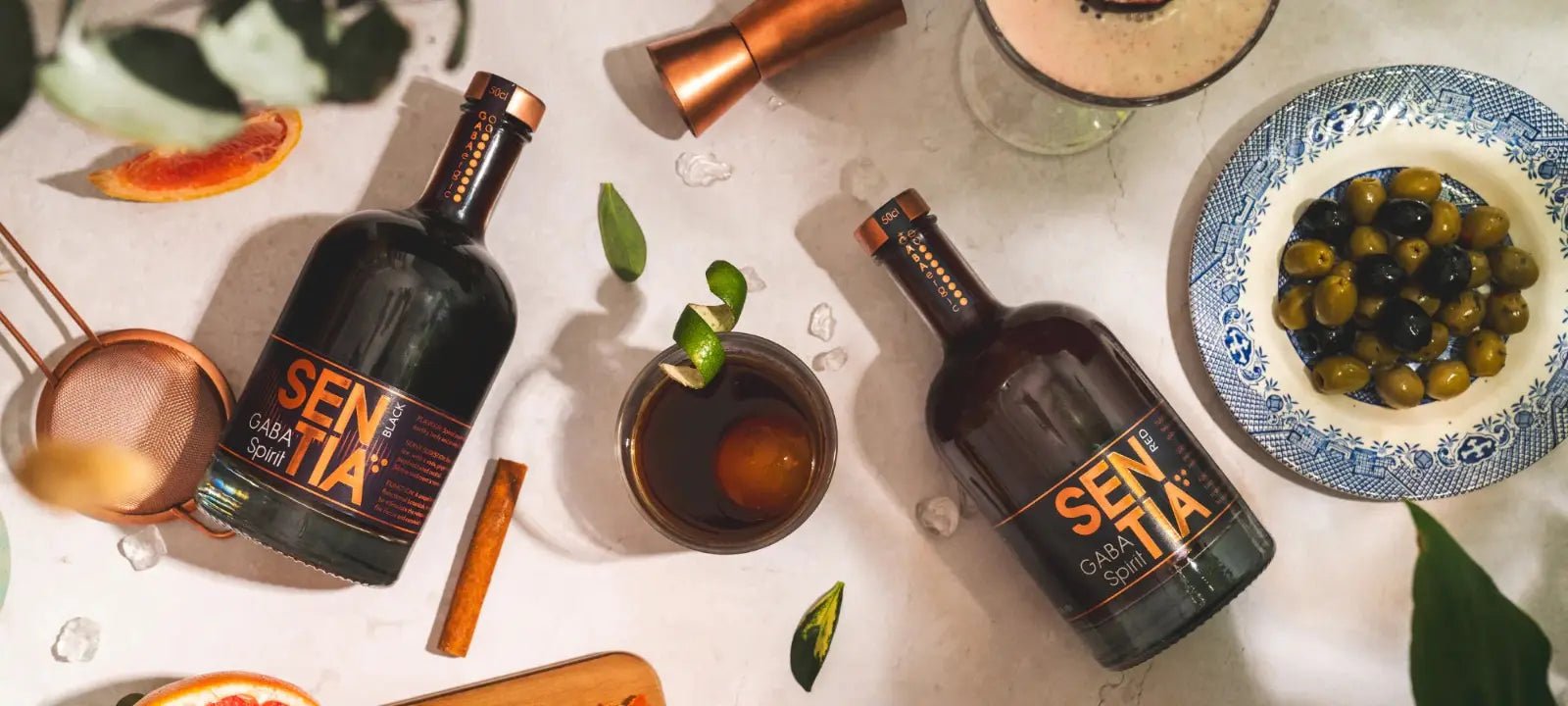 Bottles of Sentia lying on table with a bowl of olives
