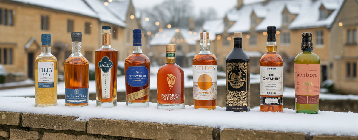 Row of whiskey bottles on a snowy ledge with a snowy landscape and buildings in the background