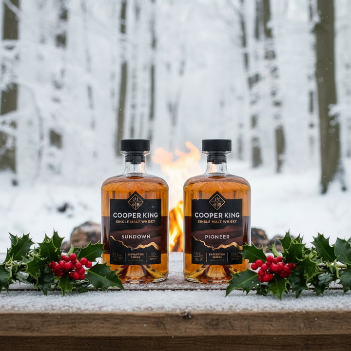 A bottle of Cooper King Pioneer Single Malt and a bottle of Cooper King Sundown Single Malt on a table in a wood