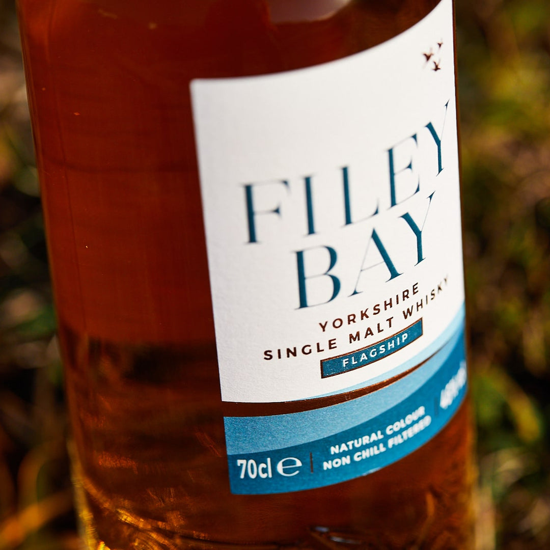 Bottle of Filey Bay Flagship Yorkshire Single Malt Whisky with a label on a grassy background