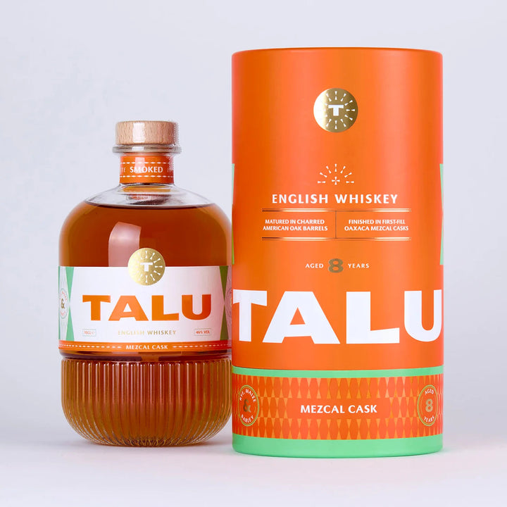 A bottle of Talu Mezcal Cask English Whiskey next to its matching orange cylindrical packaging box, set against a clean white background.