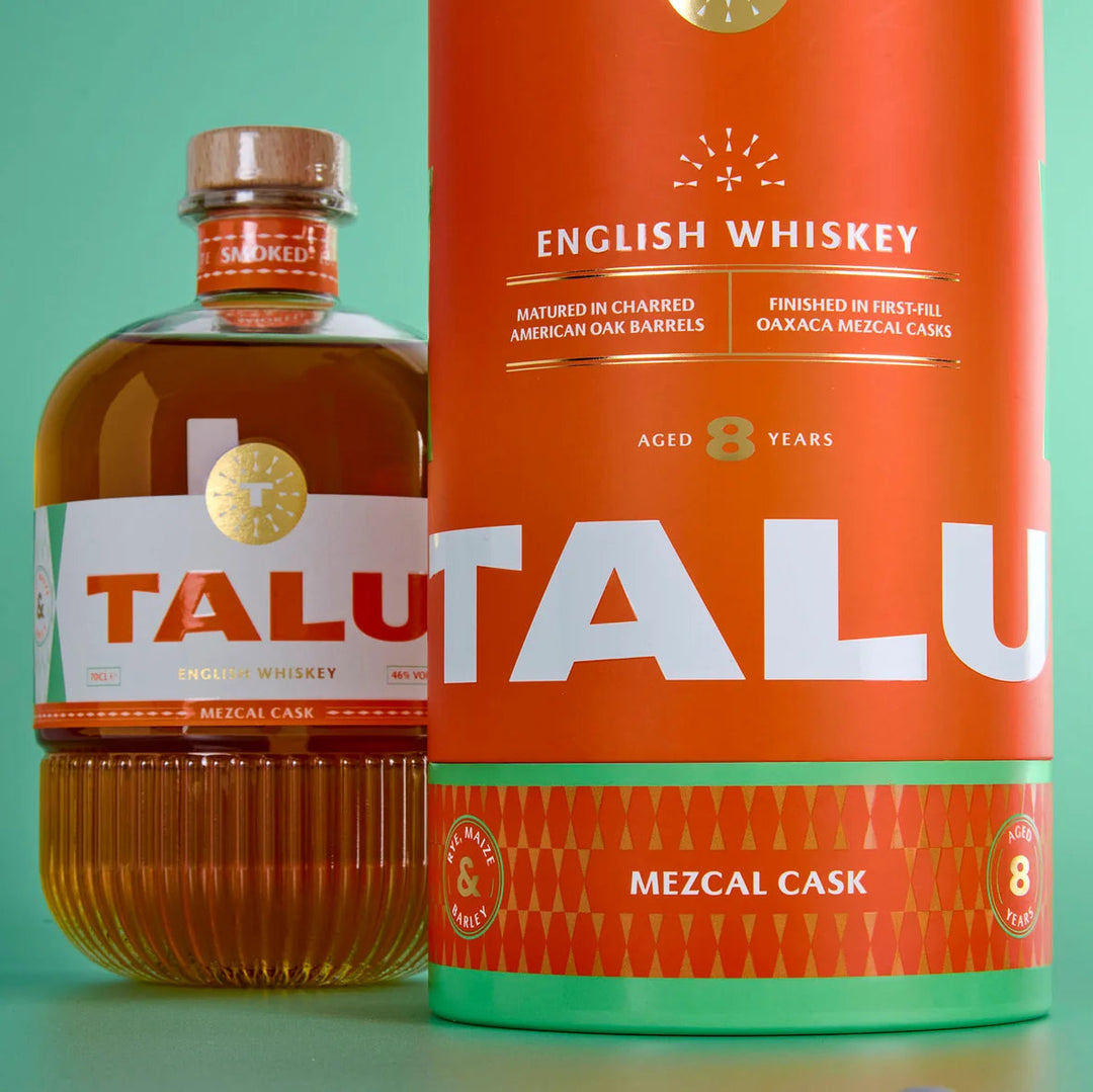 A bottle of Talu English Whiskey next to its large orange cardboard cask packaging container, set against a solid mint green background.