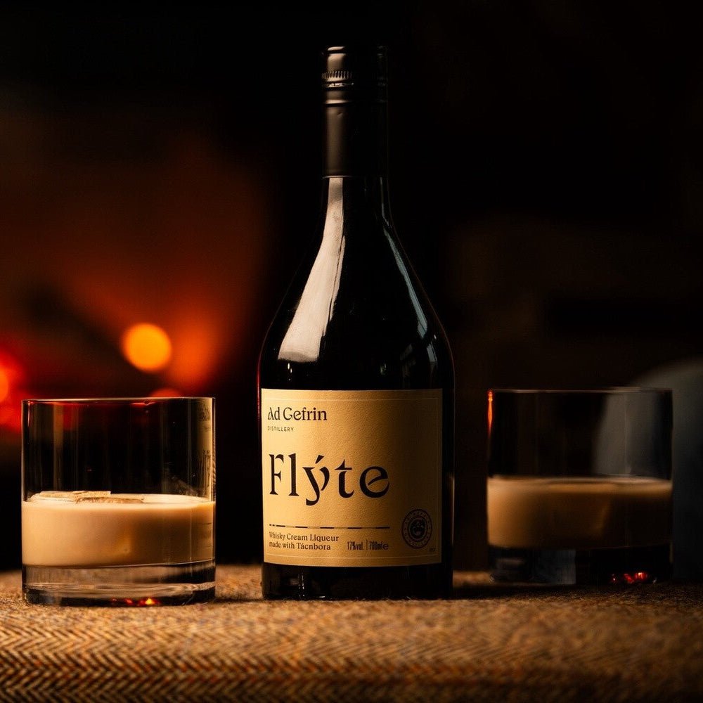 Bottle of Flyte Cream Liqueur with glasses on a table in front of a fireplace