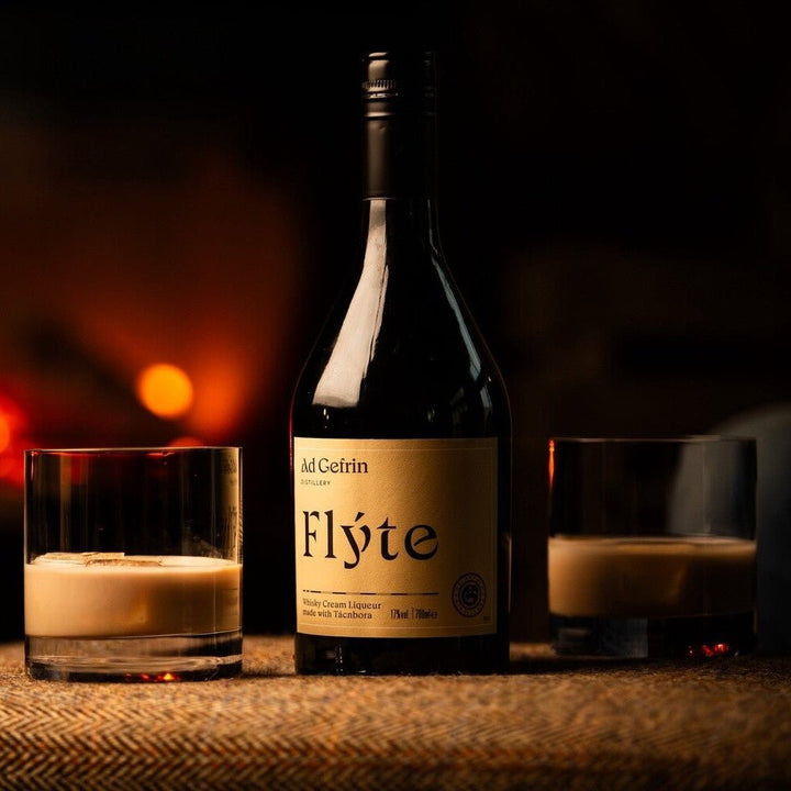 Bottle of Flyte Cream Liqueur with glasses on a table in front of a fireplace