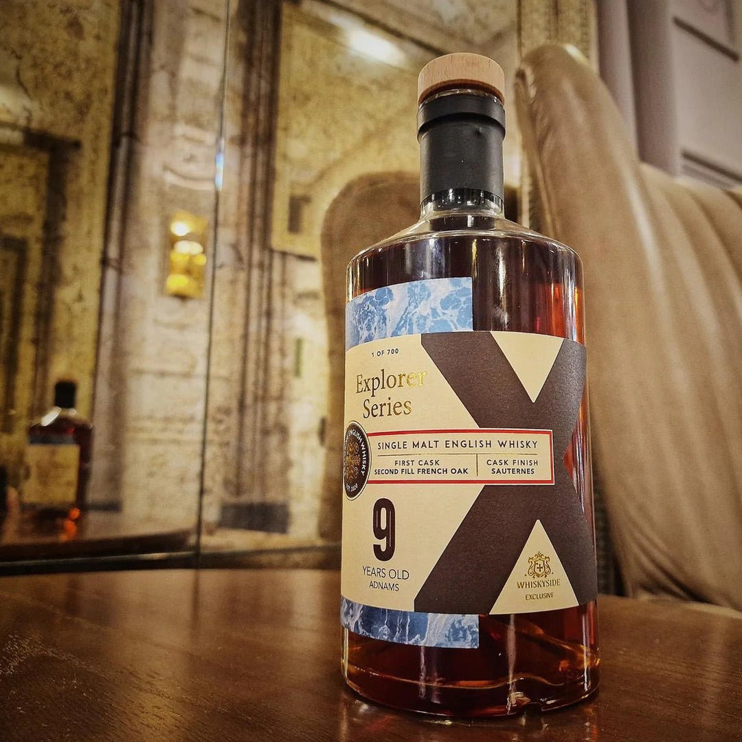 Bottle of Adnams 9 year old Sauternes Cask Whisky with a label on a wooden surface, blurred background