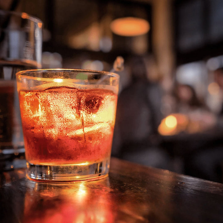 Negroni with ice in a glass on a bar counter with a blurred bar background