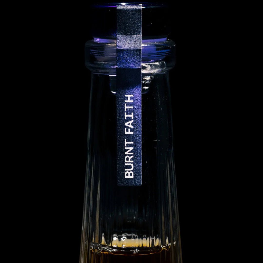 Bottle with 'Burnt Faith' label on a black background