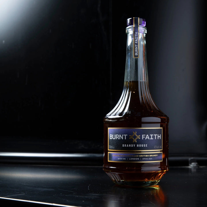 Bottle of 'Burnt Faith' brand brandy on a dark surface with a blurred background