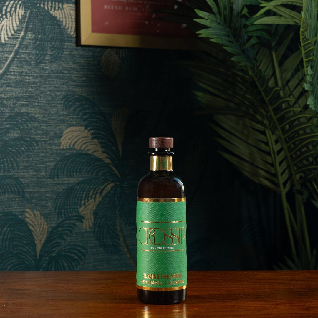 Bottle of Crossip Blazing Pineapple on a wooden surface with a decorative wall and plants in the background