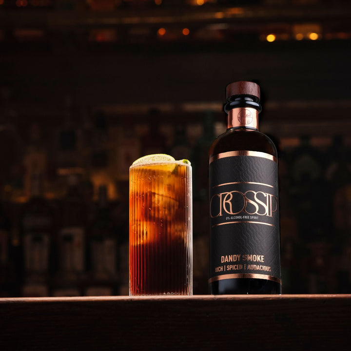 Bottle of Crossip Dandy Smoke next to a cocktail with a blurred bar background