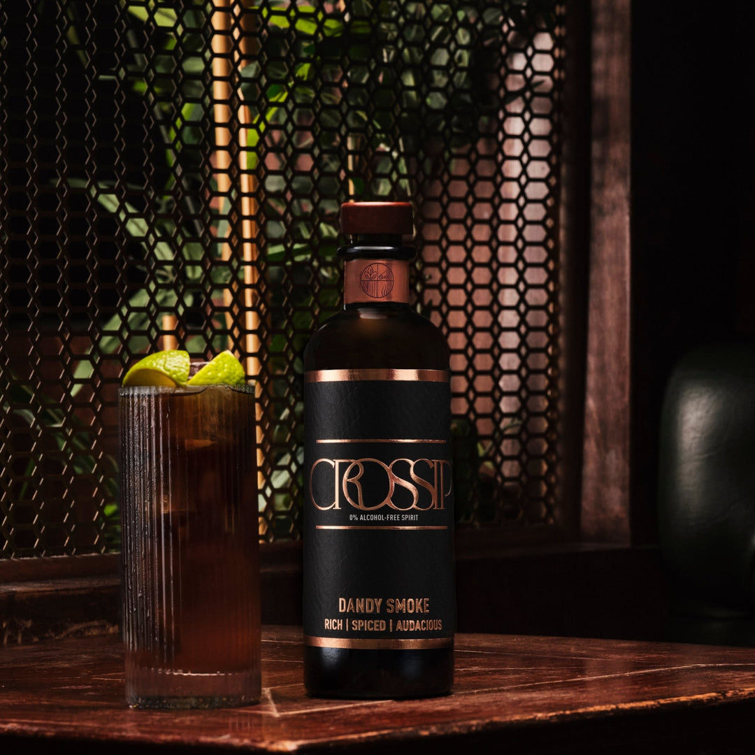 Bottle of Crossip Dandy Smoke with cola garnished with lime on a wooden surface.