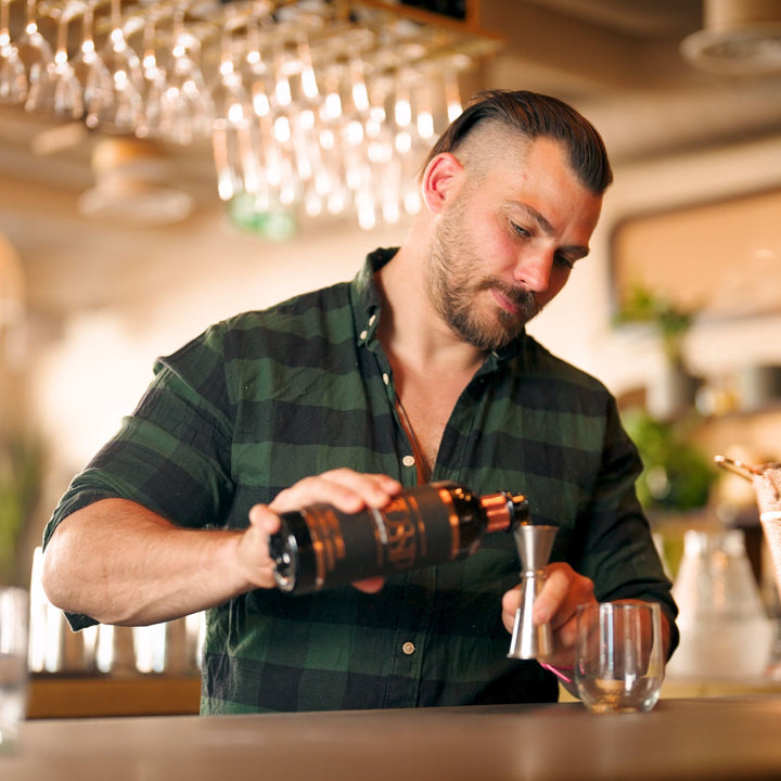 Man pouring a drink at a bar with blurred background