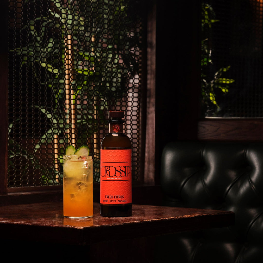 Bottle of Crossip Fresh Citrus with a cocktail on a bar counter in a dimly lit room.