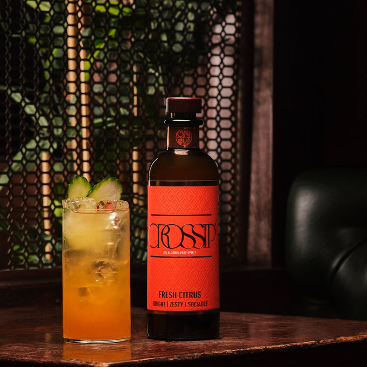 Bottle of Crossip Fresh Citrus with a cocktail on a wooden surface.