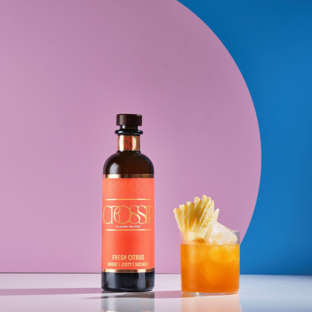 Bottle of Crossip Fresh Citrus with a cocktail garnished with pineapple on a colourful background