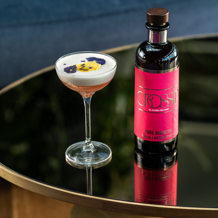 Cocktail with decorative foam and bottle on a reflective surface