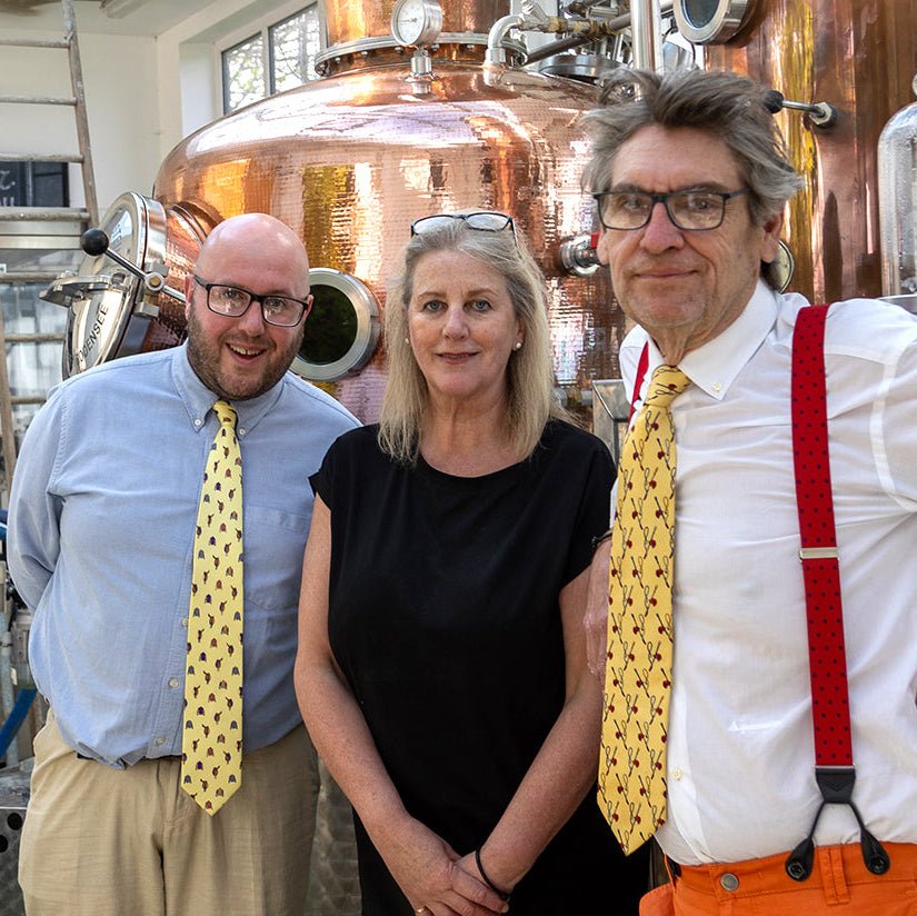 Fanny's Distillery Team standing in front of a copper still in a distillery