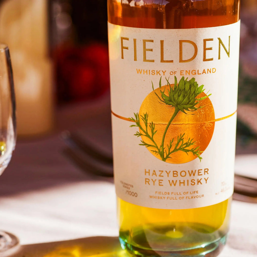 Fielden Hazybower Rye Whisky bottle on a table with a glass and candles in the background
