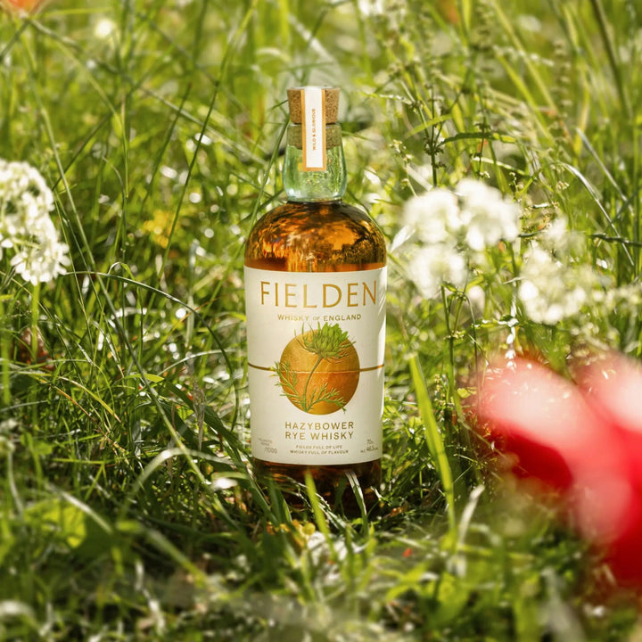 Bottle of Fielden Hazbower whisky in a grassy field with flowers