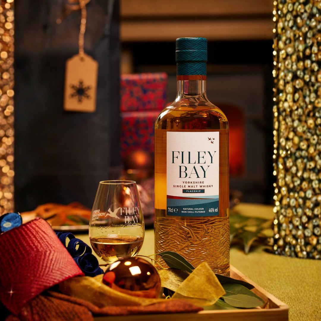 Filey Bay Yorkshire Single Malt Whisky bottle with a glass on a decorative tray in a festive setting.