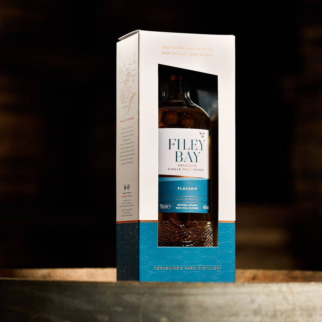 Filey Bay whisky bottle in a box on a wooden surface with a dark background