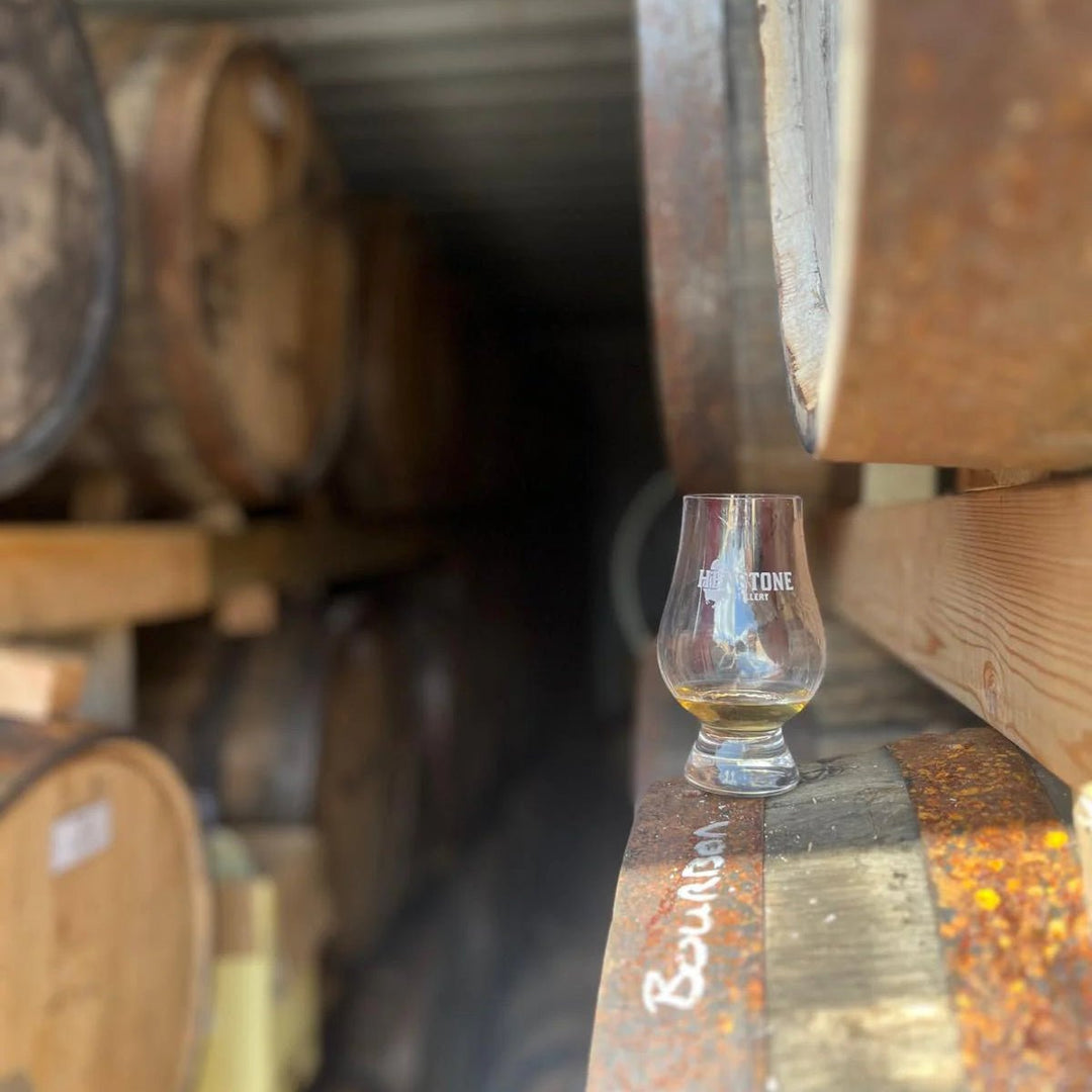 Glass of whiskey on a wooden barrel with barrels in the background