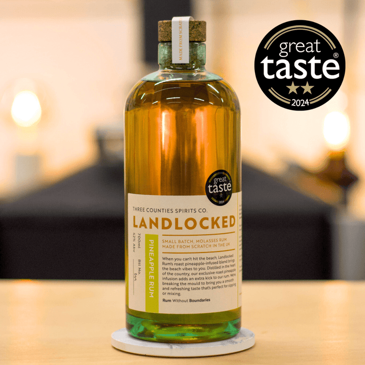 Bottle of Landlocked Pineapple Rum with 'Great Taste' award on a blurred background