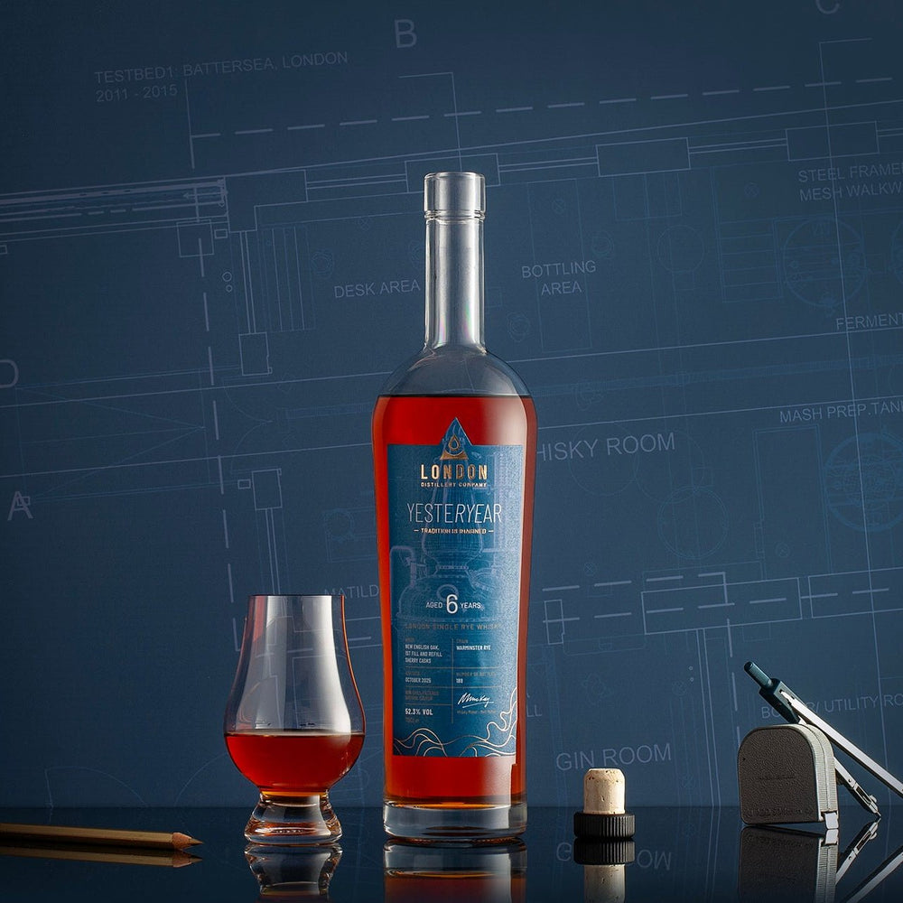 Bottle of London Distillery Company YESTERYEAR Whisky with a glass on a blue background