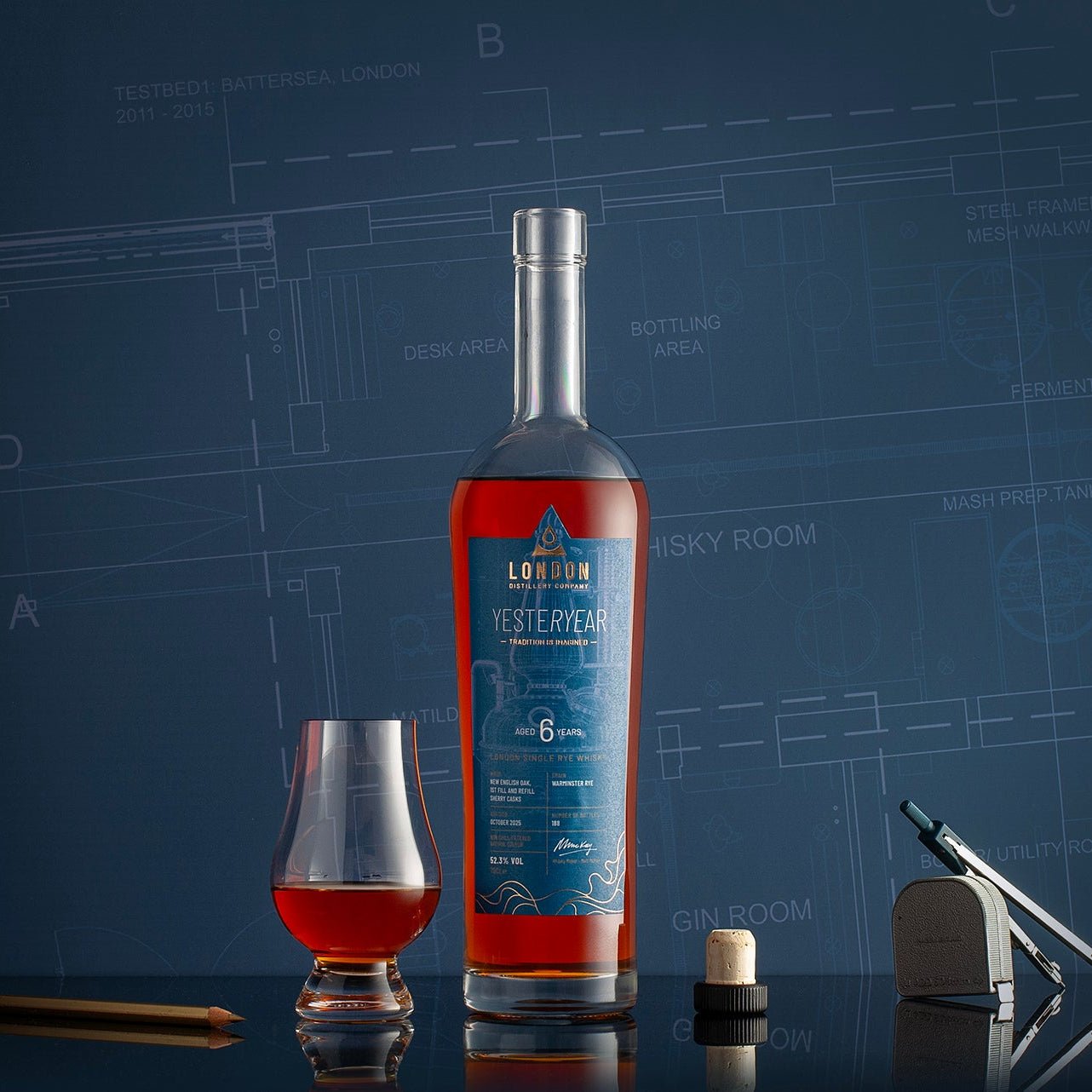 Bottle of London Distillery Company YESTERYEAR Whisky with a glass on a blue background