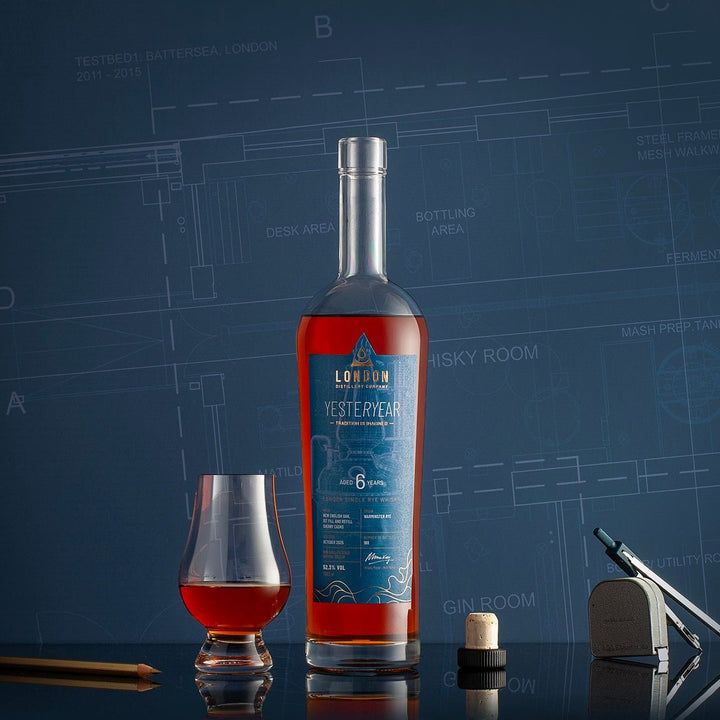Bottle of London Distillery Company YESTERYEAR Whisky with a glass on a blue background