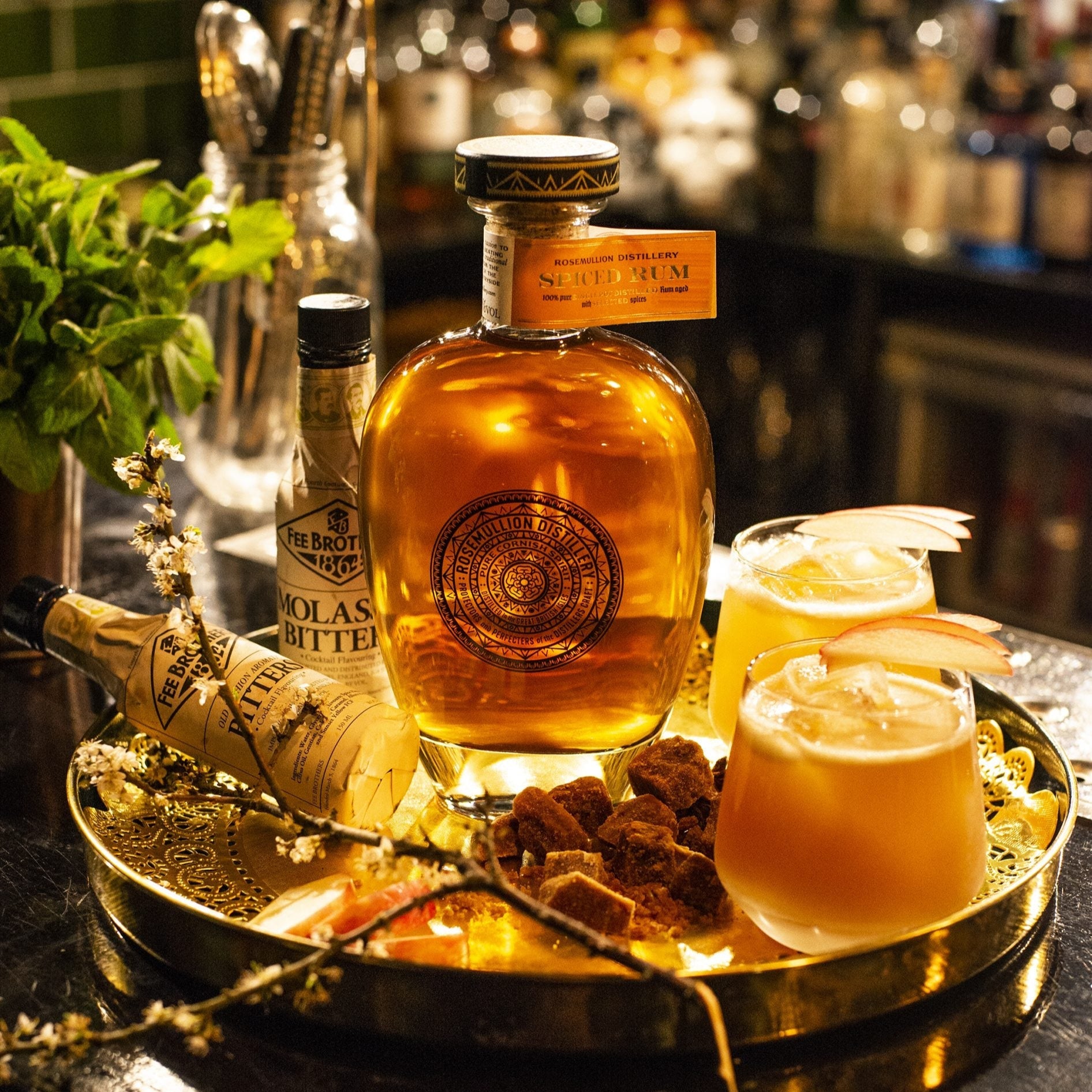 Bottle of Rosemullion Spiced Rum with two glasses on a tray in a bar setting