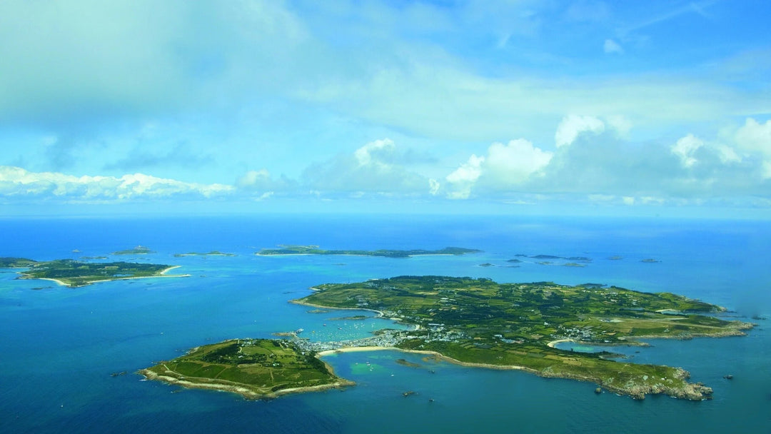 Aerial view of the Scilly Isles with lush greenery surrounded by blue water.