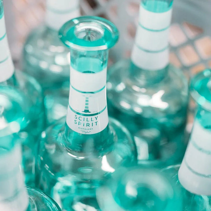 Teal glass bottles with white labels with Scilly Spirit on them