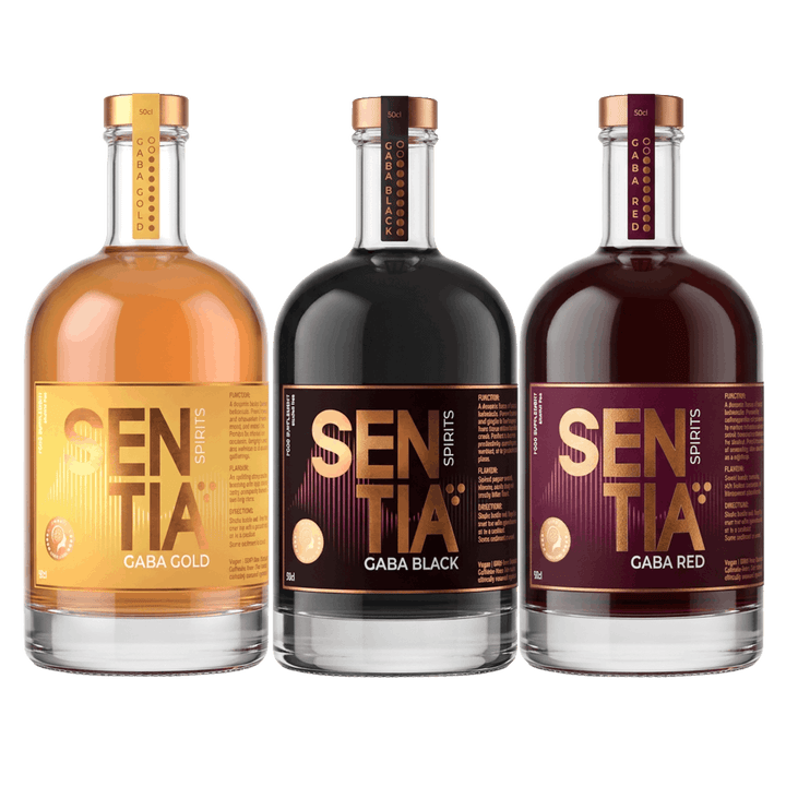Three bottles of SENTIA Spirits gaba supplements lined up against a solid black background. From left to right, the bottles contain Gaba Gold (amber liquid), Gaba Black (dark liquid), and Gaba Red (deep red-brown liquid), each with a metallic copper cap and a matching gradient label.