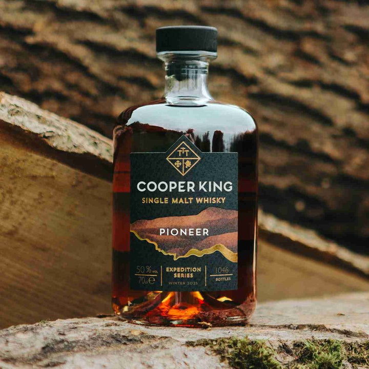 Cooper King Pioneer Single Malt Whisky bottle on a wooden surface with a rustic background