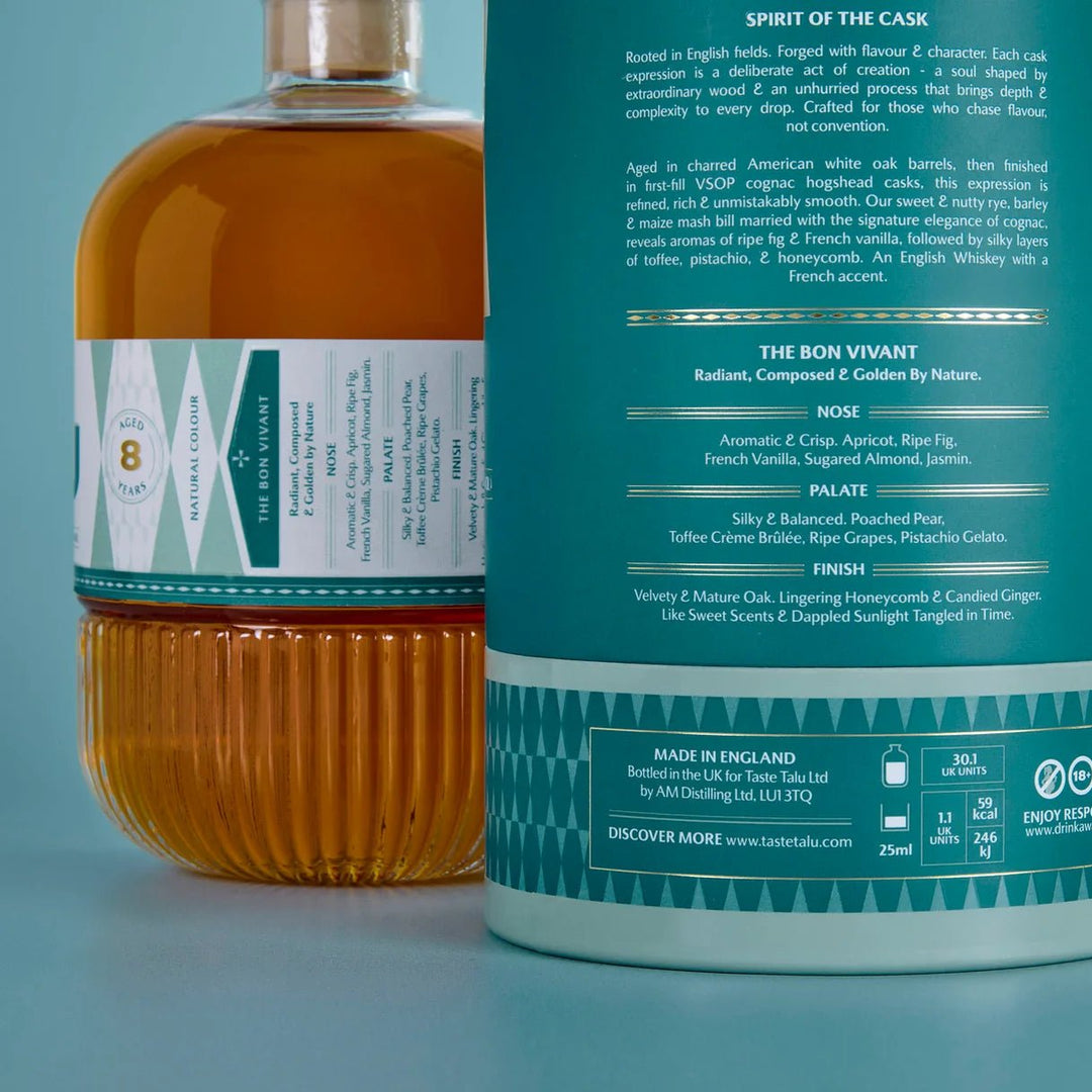Close-up of a bottle of Taste Talu Cognac Cask Whiskey with its back label facing the camera, next to the front bottle showing amber liquid and a teal-and-white label.