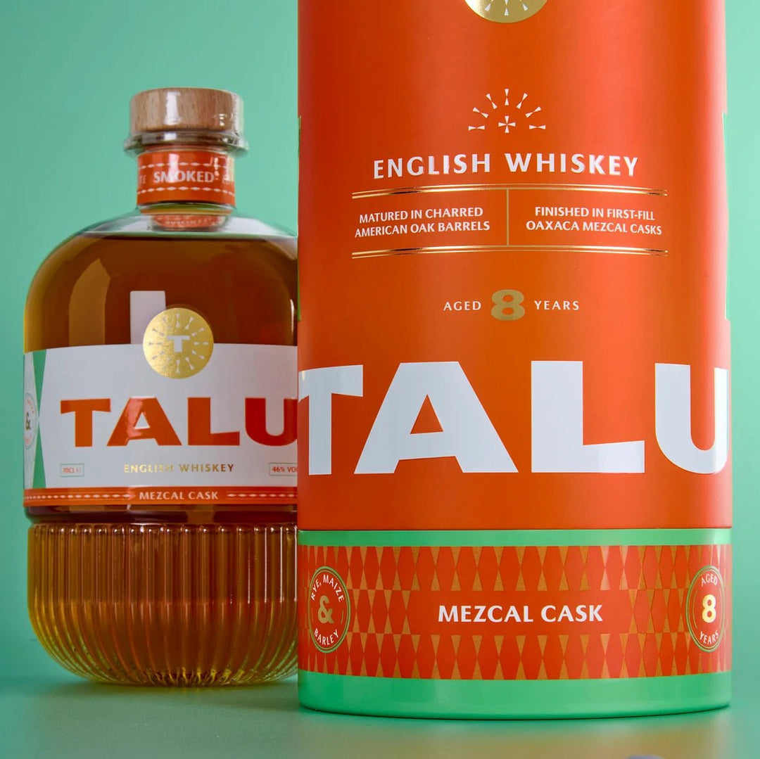 A bottle of Talu English Whiskey next to its large orange cardboard cask packaging container, set against a solid mint green background.