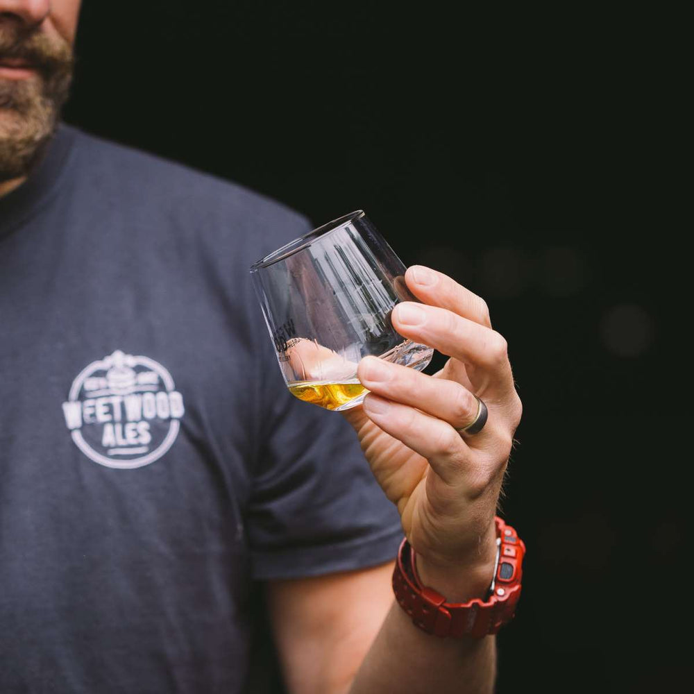 Person holding a glass of whisky with a dark background