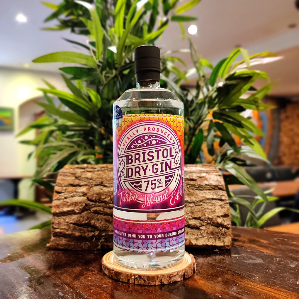 Bottle of Bristol Dry Gin Turbo Island Edition 75% alcohol on a wooden coaster with plants in the background