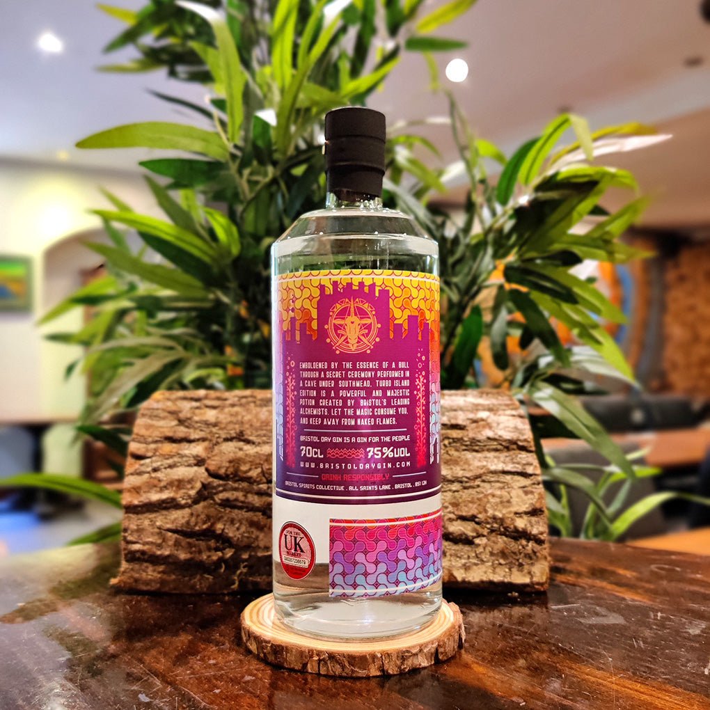 Back label of Bottle of Bristol Dry Gin Turbo Island Edition 75% alcohol on a wooden coaster, surrounded by plants.