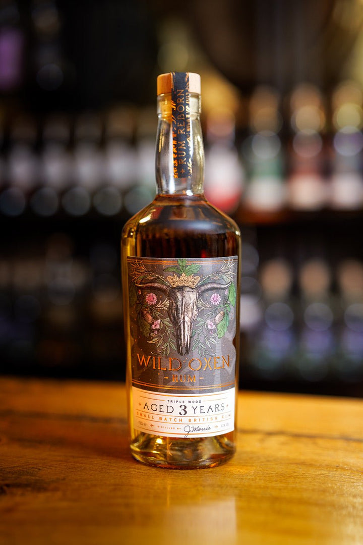 Bottle of Wild Oxen 3 year old rum on a wooden surface with blurred bottles in the background