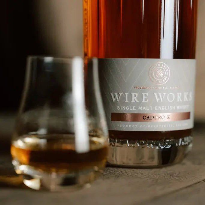 Bottle and glass of Wire Work Caduro X whisky on a wooden surface