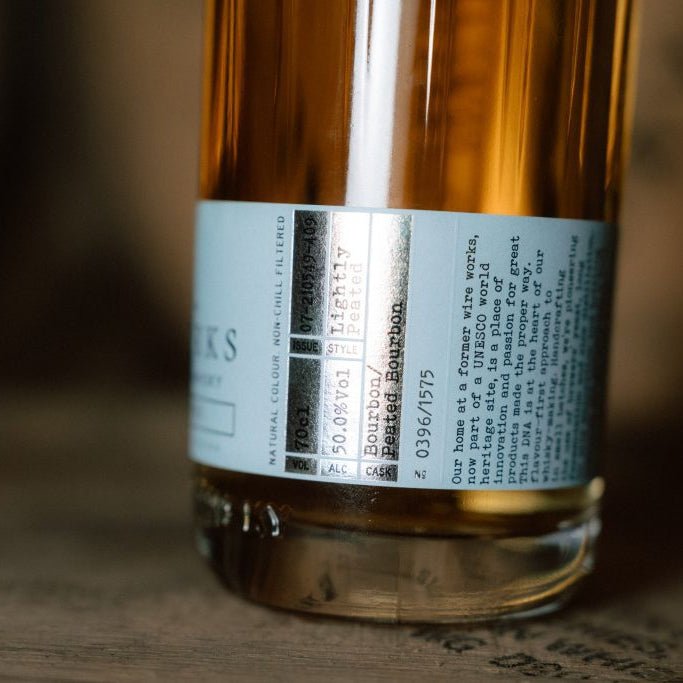Bottle of Wire Works Coastal Smoke whisky with a label on a wooden surface