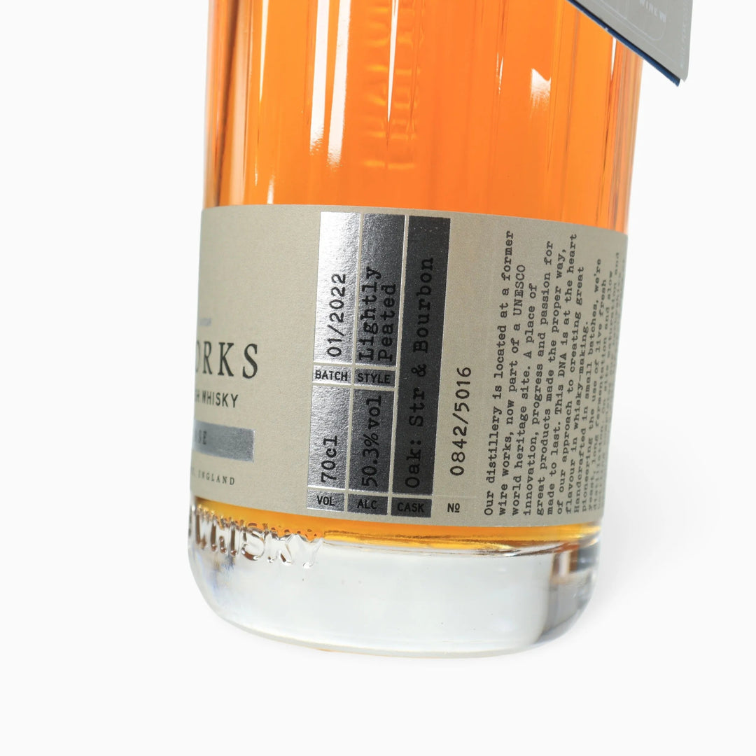 Closeup of a bottle of White Peak Distillery First release English Whisky showing side label on a white background